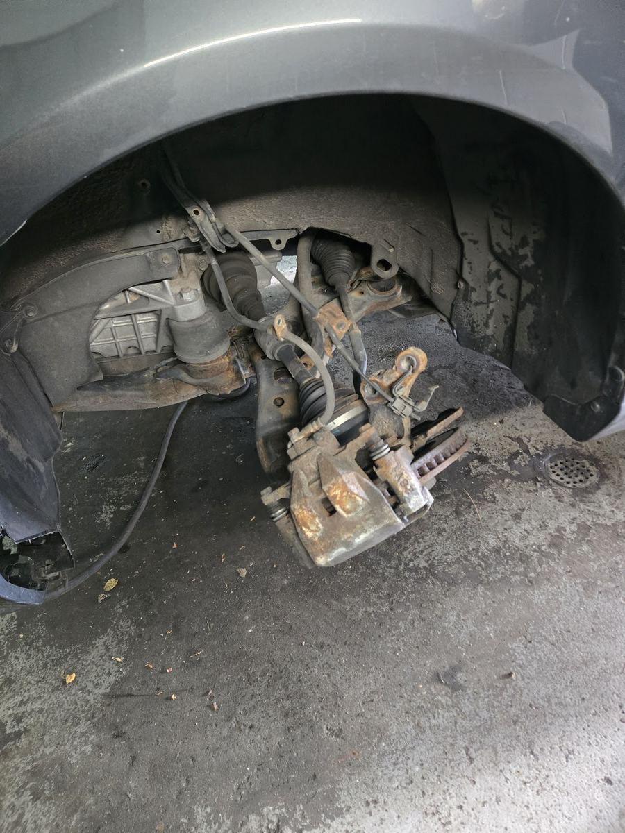 A brake caliper and suspension knuckle exposed in a wheel well