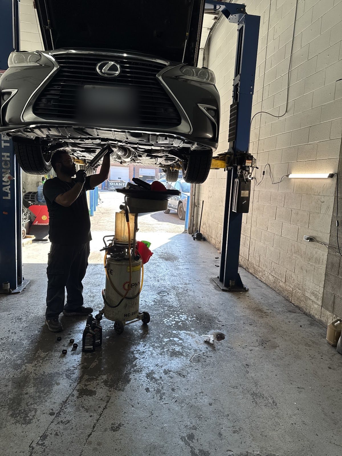 Kamal working under a car on the hoist at Kam Auto Repair, Mississauga