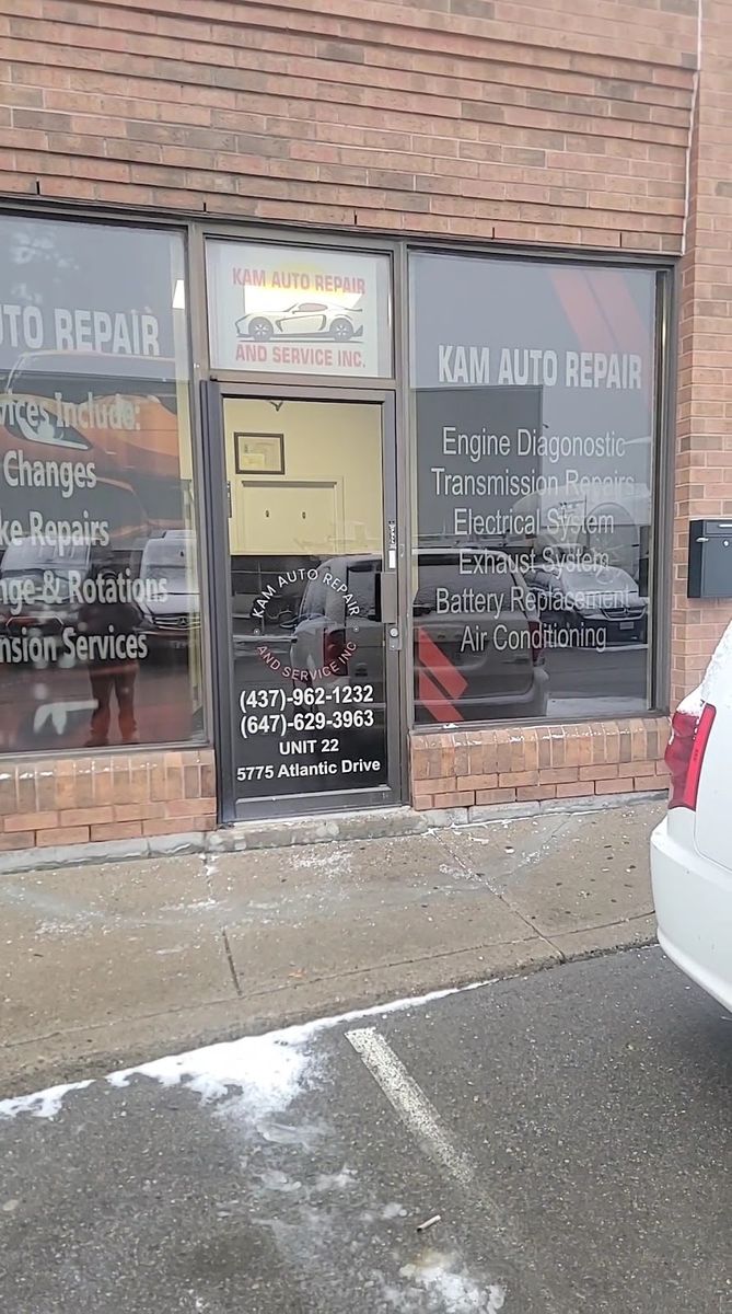 The front door of Unit 22 with the Kam Auto Repair sign and service list